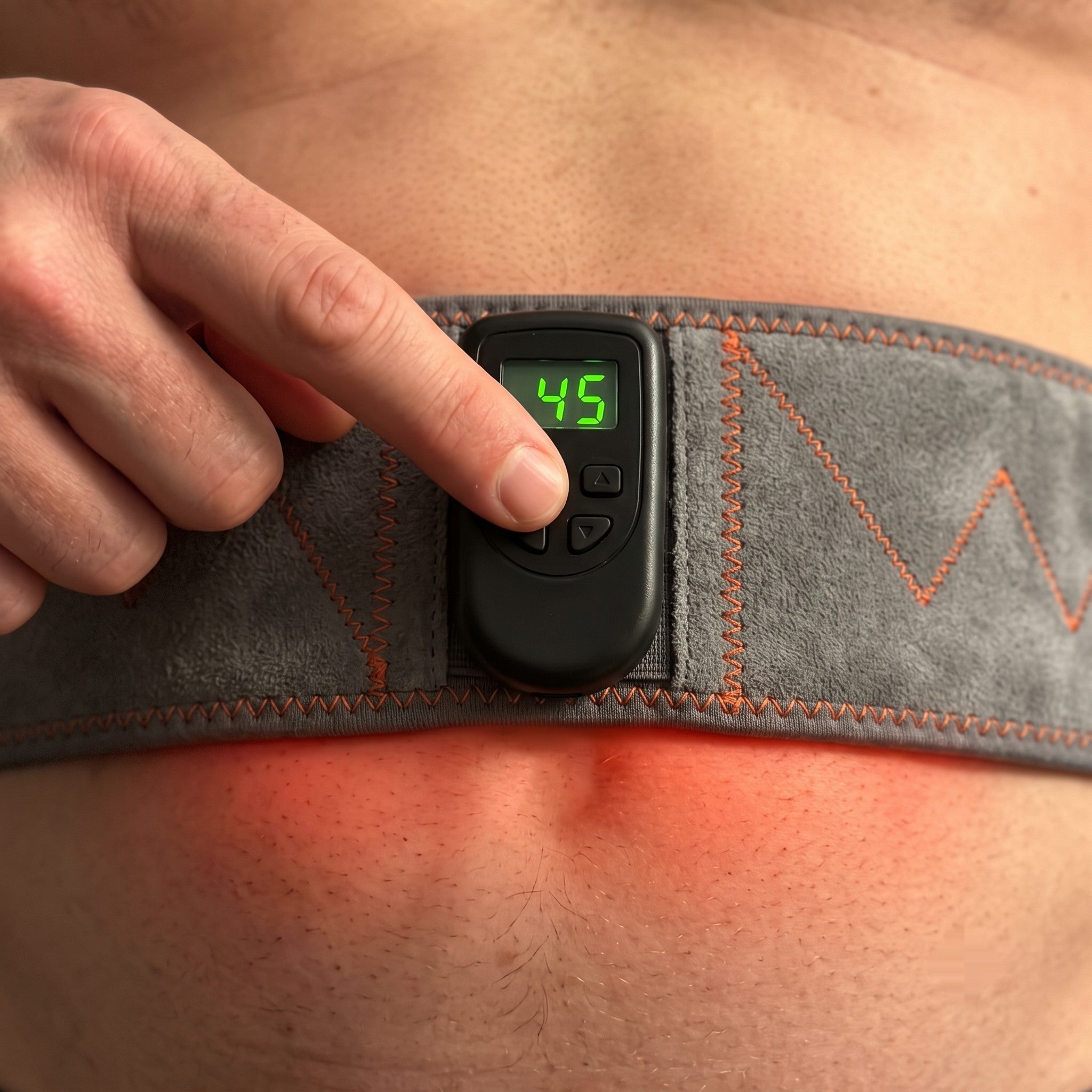 Step 2: finger pressing the belt's control button as the red LED clusters light up